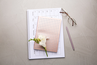 Flat lay composition with calendar, notebook and beautiful flower on grey table