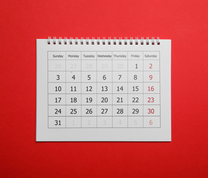Paper calendar on red background, top view