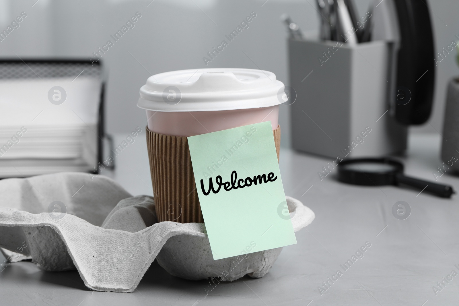 Image of Sticky note with word Welcome attached to paper cup of coffee on office desk