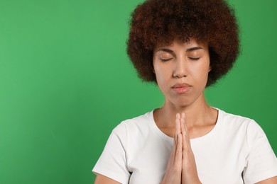 Photo of Woman with clasped hands praying to God on green background. Space for text