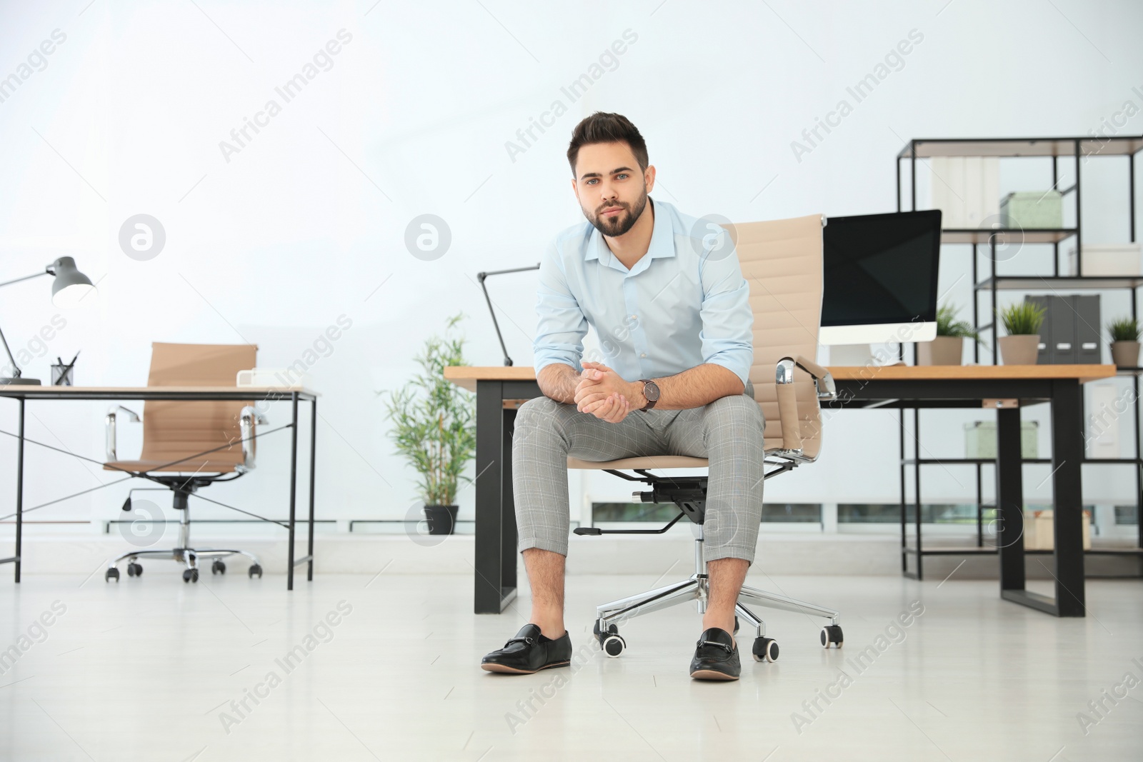 Photo of Young businessman sitting in office chair at workplace. Space for text