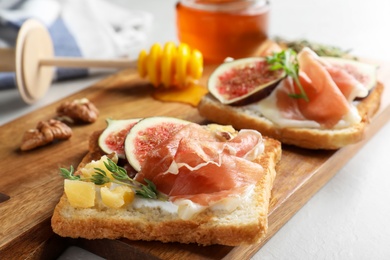 Photo of Delicious sandwiches with figs, proscuitto and cheese on light table, closeup