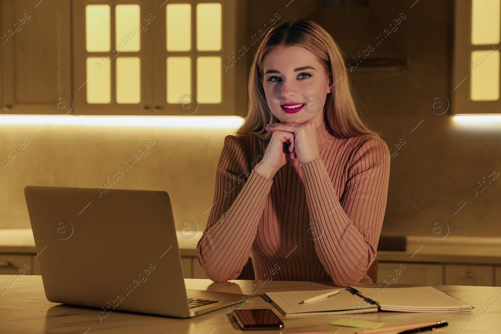 Photo of Home workplace. Portrait of happy woman near laptop at marble desk in kitchen