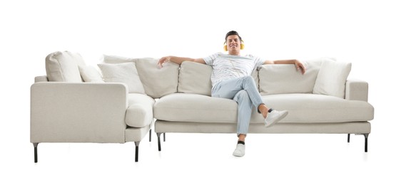 Man listening to music on comfortable sofa against white background