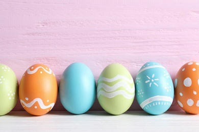 Colorful painted Easter eggs on table against wooden background, space for text