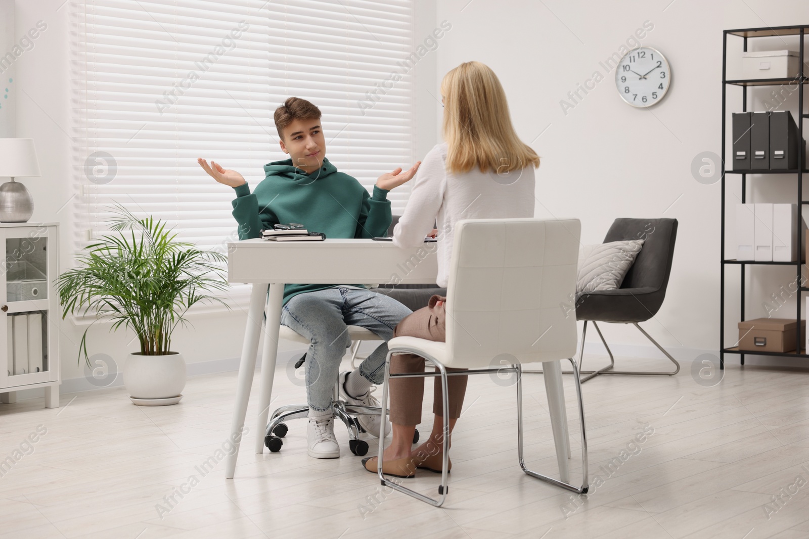 Photo of Psychologist working with teenage boy at table in office