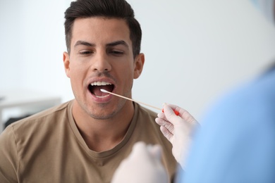 Photo of Doctor taking sample for DNA test from man in clinic