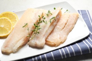 Photo of Pieces of raw cod fish and lemon on table, closeup