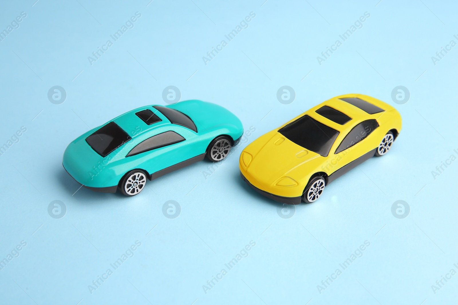 Photo of Two bright cars on light blue background. Children`s toys