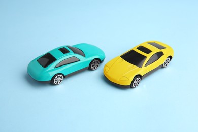 Photo of Two bright cars on light blue background. Children`s toys