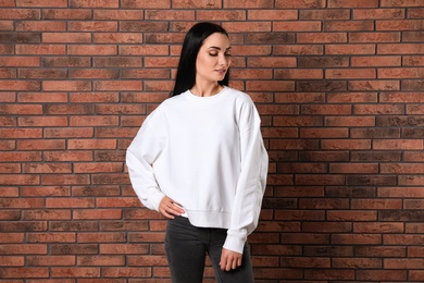 Photo of Portrait of young woman in sweater at brick wall. Mock up for design