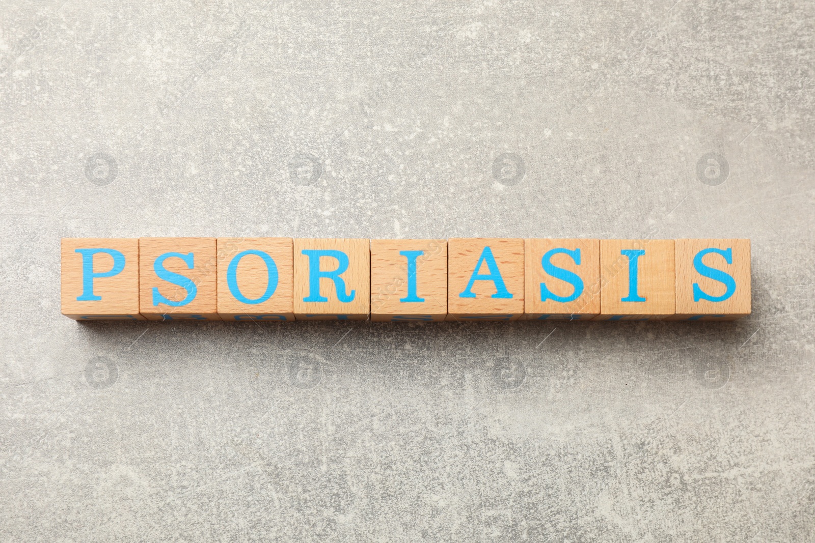 Photo of Word Psoriasis made of wooden cubes with letters on light gray textured table, top view