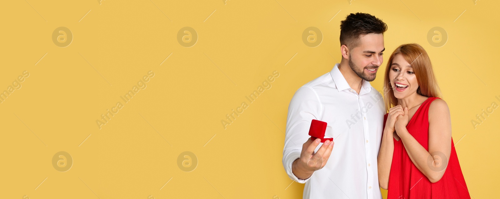 Image of Man with engagement ring making marriage proposal to girlfriend on yellow background, space for text. Banner design