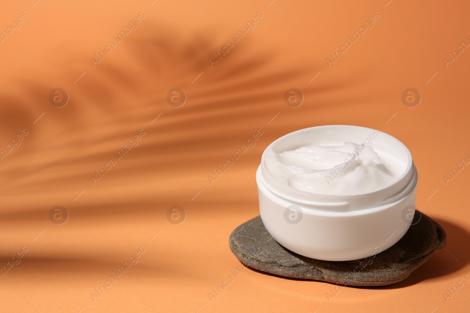 Photo of Cosmetic product and spa stone on orange background, space for text