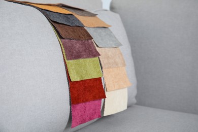 Photo of Catalog of colorful fabric samples on grey sofa