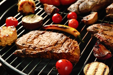 Photo of Fresh grilled meat steaks and vegetables on barbecue grate