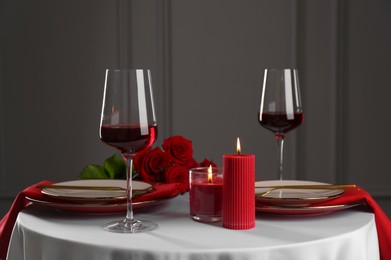 Photo of Place setting with candles and roses on white table. Romantic dinner