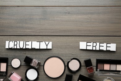 Photo of Flat lay composition with words Cruelty Free and different cosmetic products not tested on animals against wooden background. Space for text