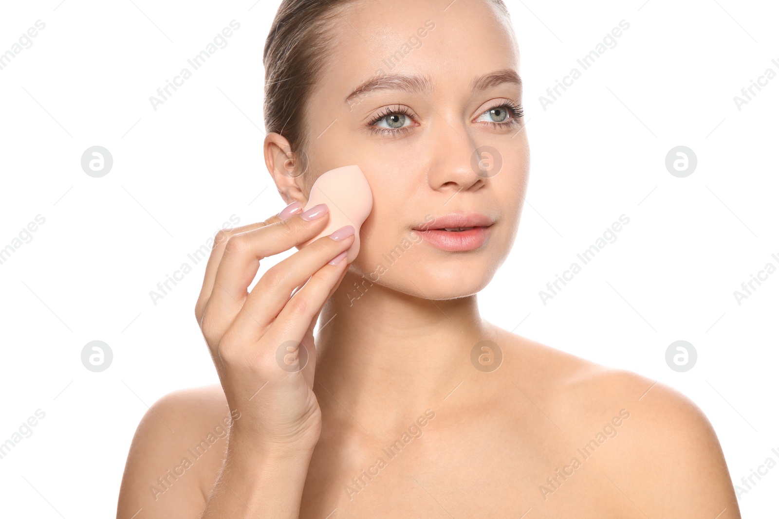 Photo of Young woman applying foundation on her face against white background