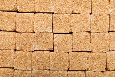 Brown sugar cubes as background, top view