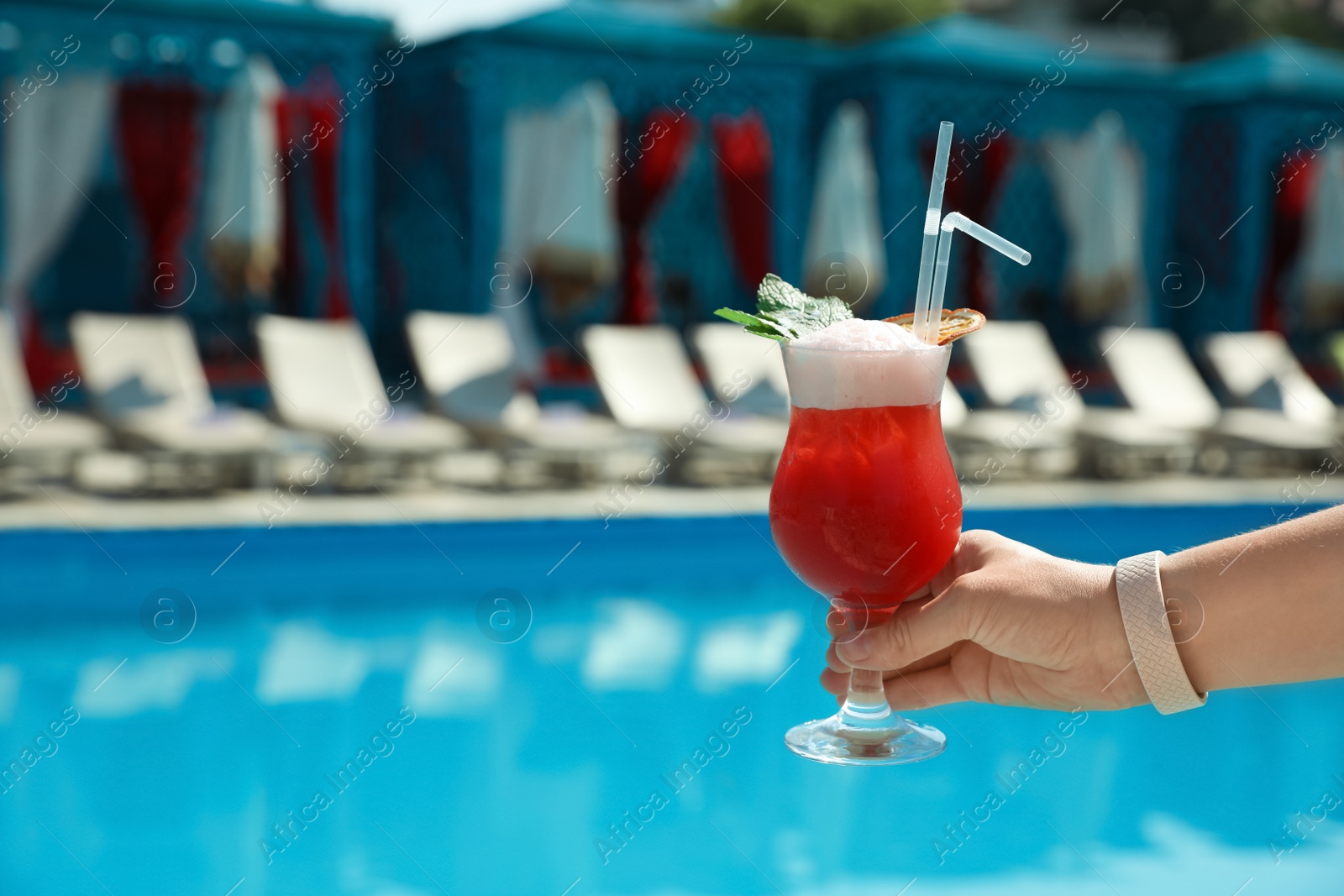 Photo of Woman with refreshing cocktail near swimming pool outdoors, closeup. Space for text