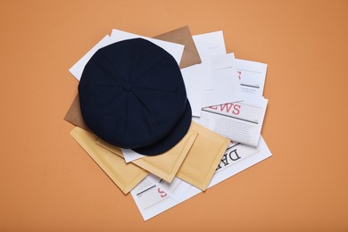 Photo of Postman hat, newspapers and mails on light brown background, flat lay