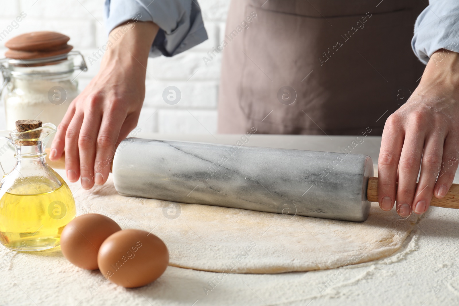 Photo of Woman rolling raw dough at table, closeup