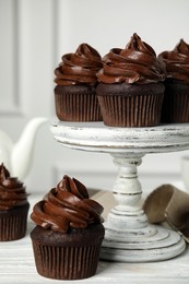 Delicious chocolate cupcakes with cream on white wooden table
