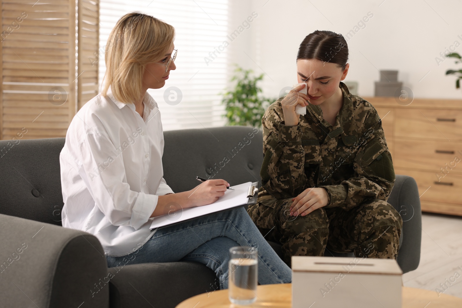 Photo of Psychotherapist working with military woman on sofa in office