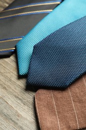 Photo of Different neckties on light wooden table, closeup