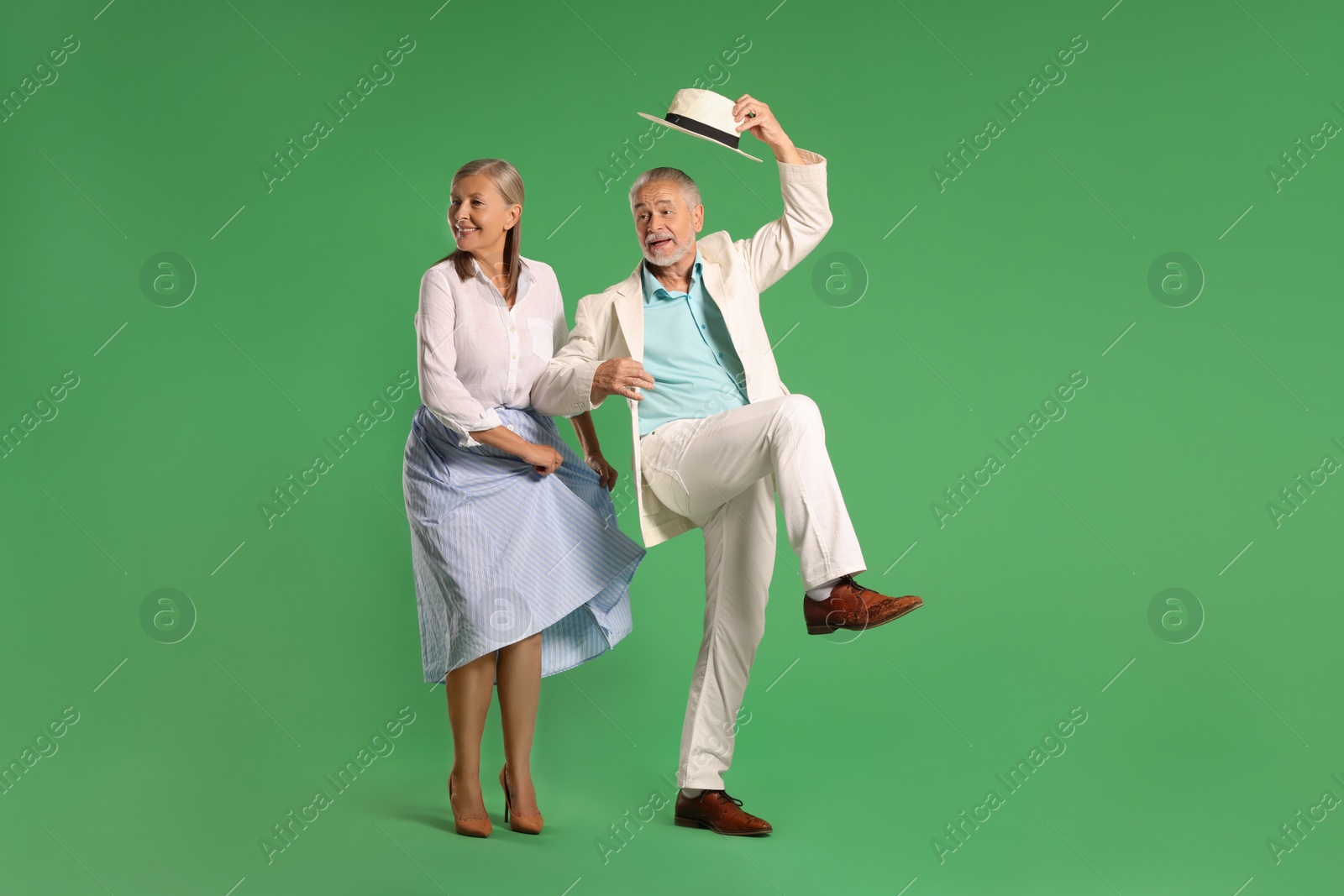 Photo of Senior couple dancing together on green background