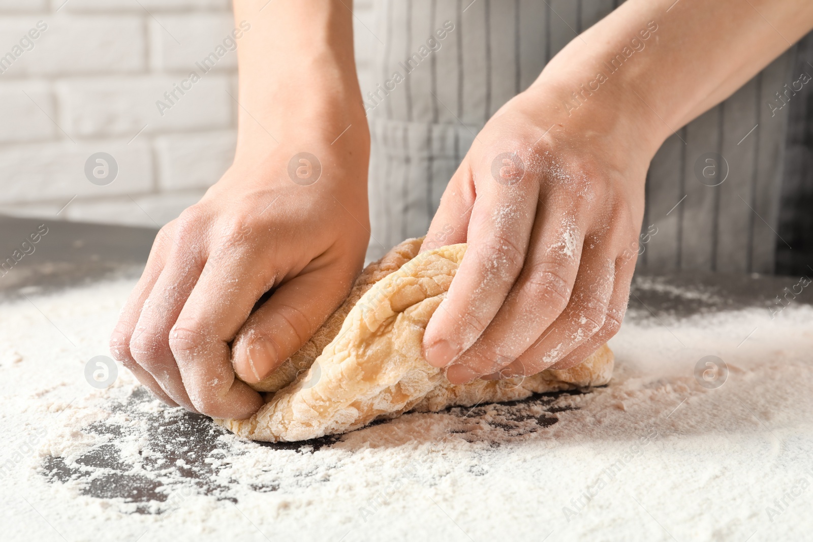 Photo of Young woman kneading dough for pasta on table