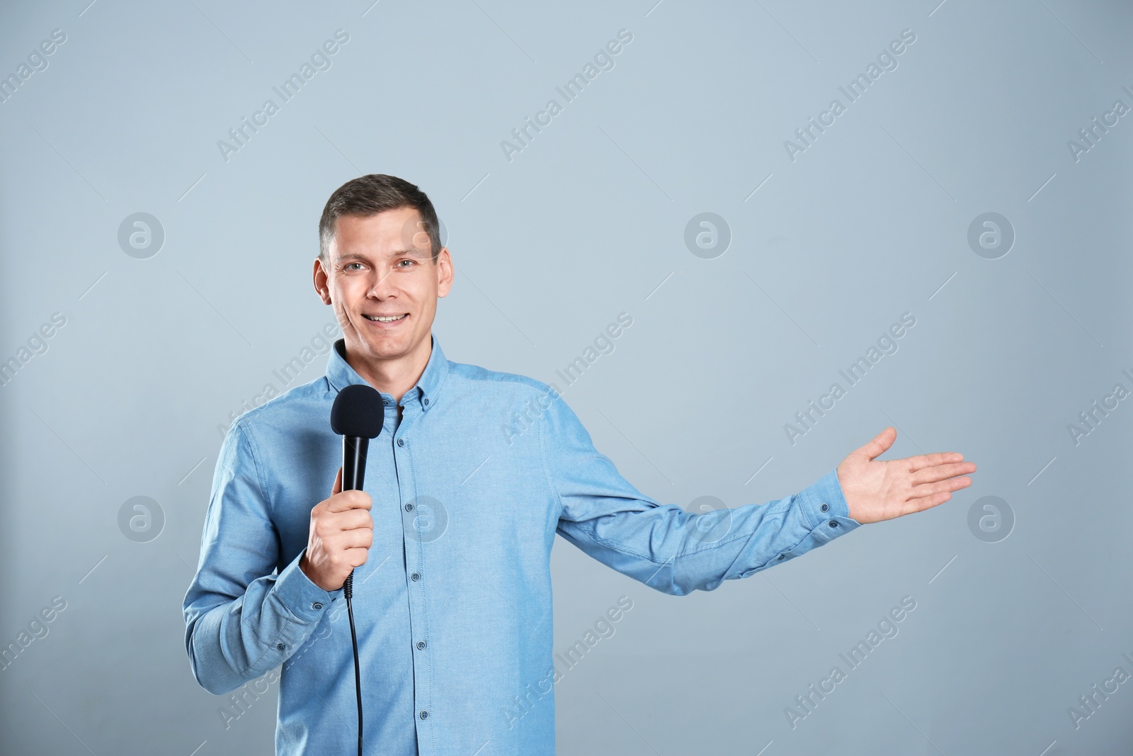 Photo of Male journalist with microphone on grey background