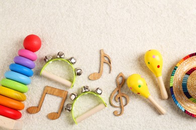 Photo of Baby song concept. Wooden notes, kids musical instruments and toys on beige carpet, flat lay. Space for text