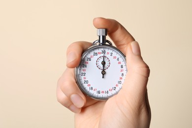 Woman holding vintage timer on beige background, closeup. Space for text