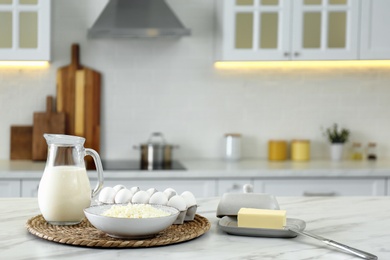 Photo of Different dairy products and eggs on white table in modern kitchen. Space for text