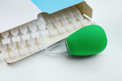 Photo of Package with single dose ampoules of sterile isotonic sea water solution and nasal aspirator on white background, closeup