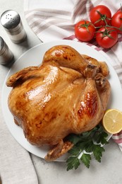 Photo of Tasty roasted chicken with parsley, lemon and tomatoes on light grey table, flat lay