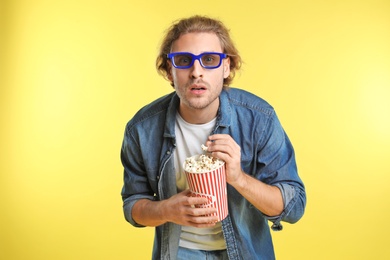 Photo of Emotional man with 3D glasses and popcorn during cinema show on color background