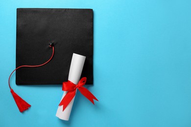 Photo of Graduation hat and diploma on light blue background, flat lay. Space for text