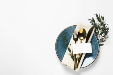 Stylish table setting with cutlery, blank card and eucalyptus leaves on white background, top view. Space for text
