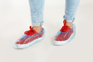 Photo of Woman with blue shoe covers worn over sneakers on white background, closeup