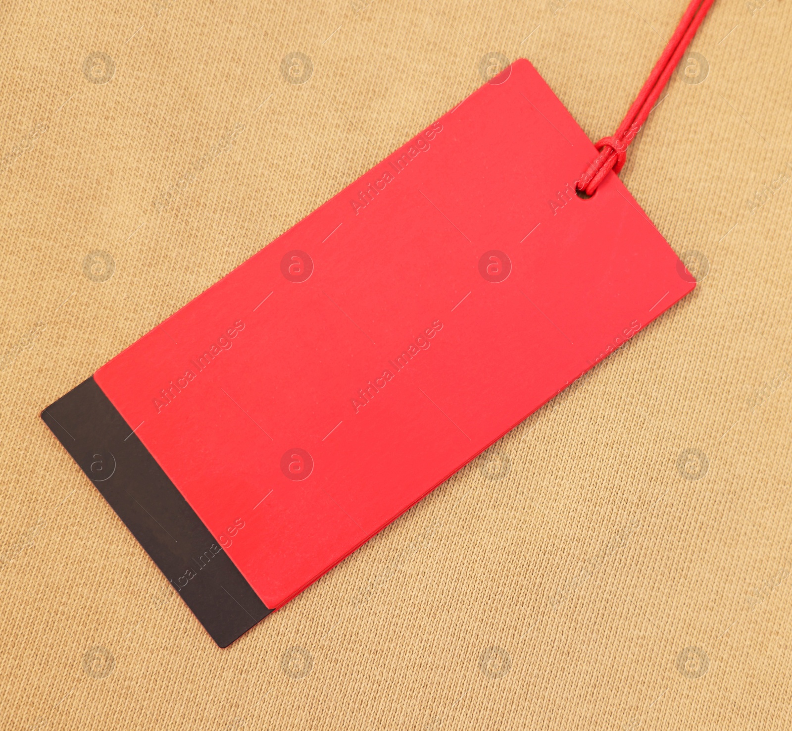 Photo of Red tag on beige garment, top view. Space for text