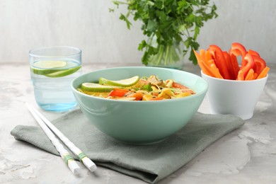 Photo of Stir-fry. Delicious cooked noodles with chicken and vegetables in bowl served on gray textured table