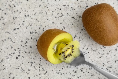 Photo of Spoon in fresh ripe yellow kiwi and fruit on white table with pattern, flat lay