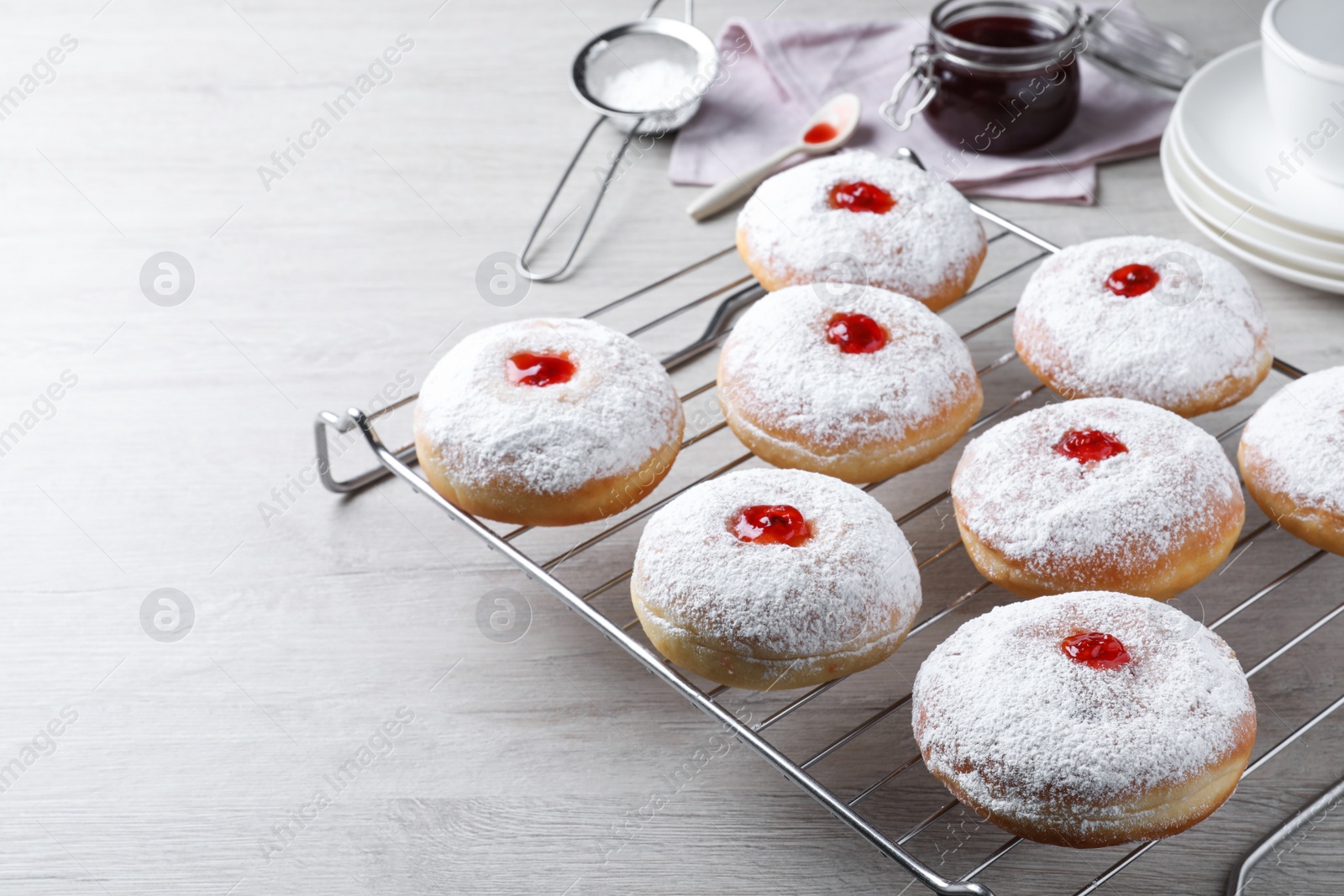 Photo of Many delicious donuts with jelly and powdered sugar on wooden table. Space for text