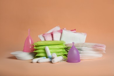 Photo of Menstrual pads and other period products on pale orange background