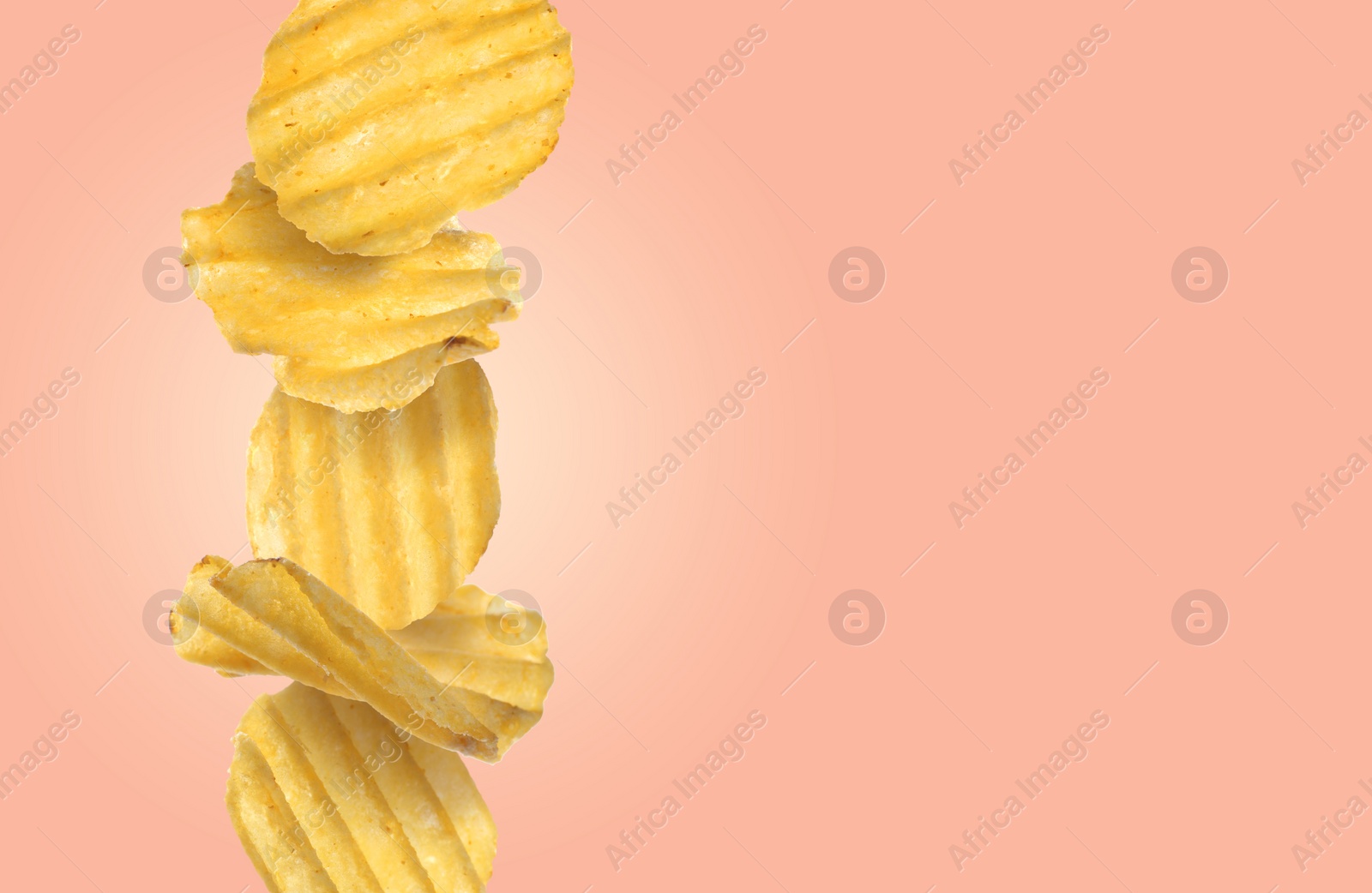 Image of Stack of tasty ridged potato chips on pale coral background, space for text