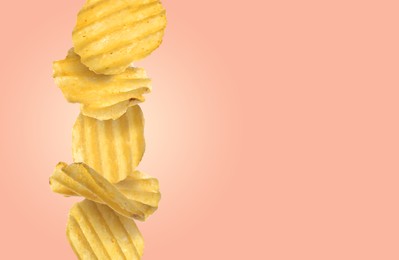 Stack of tasty ridged potato chips on pale coral background, space for text