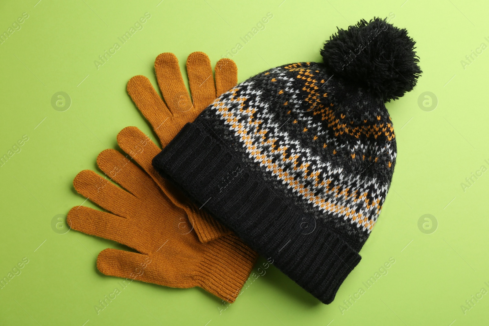Photo of Woolen gloves and hat on green background, flat lay